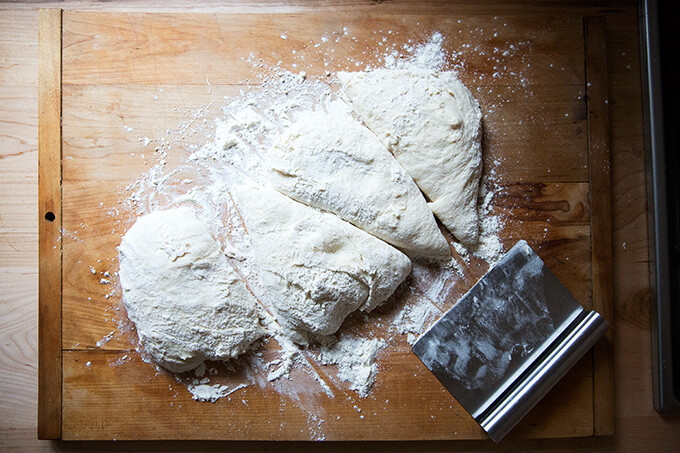 A floured work surface topped with homemade pizza dough, divided into 4 portions. 
