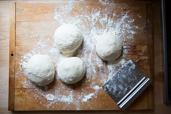 A floured work surface topped with 4 rounds of homemade pizza dough.
