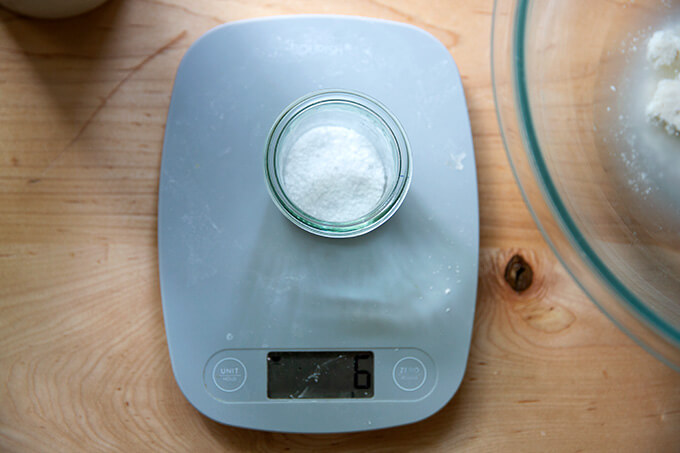 A scale with 6 grams of salt measured in a small glass jar on top.