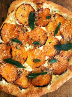 A roasted butternut squash and crispy sage pizza on a board.
