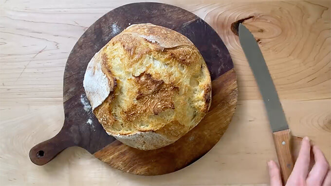 A baked loaf of sourdough bread on a cutting board. 