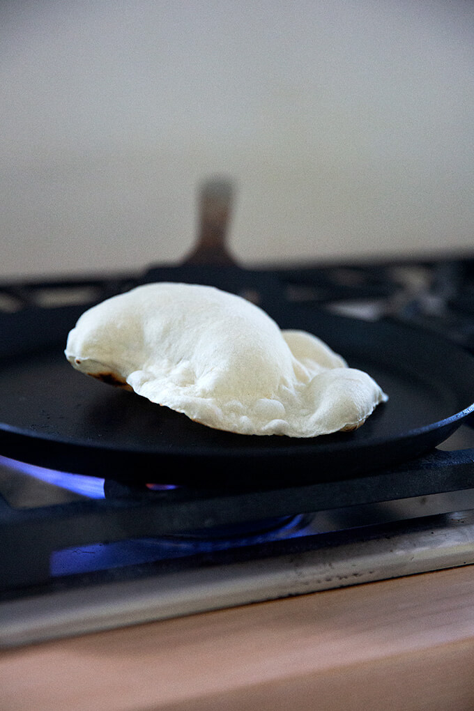 A sourdough flour tortilla cooking in a skillet stovetop.