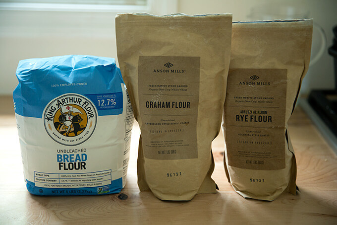 Three flours on a counter top: King Arthur Flour bread flour, Anson Mills Graham Flour, Anson Mills Rye flour.