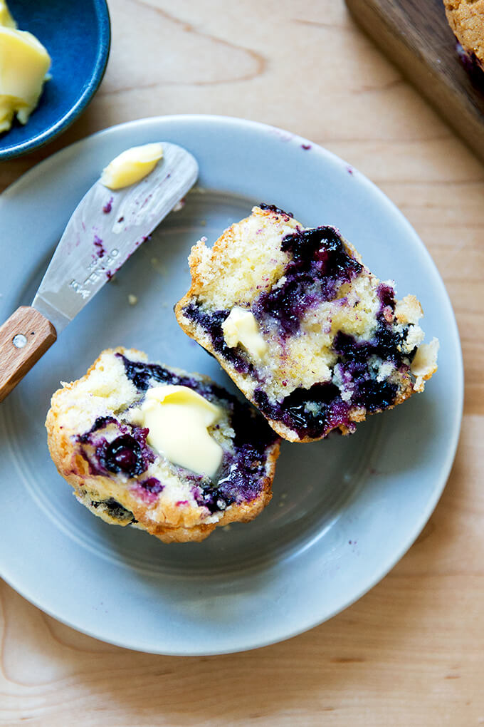 A halved blueberry muffin spread with butter.