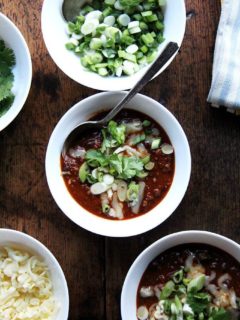 A bowl of weeknight chili topped with scallions and cheddar.