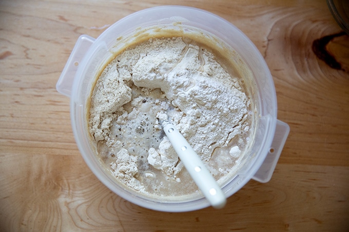 A 2-quart container holding sourdough starter, flour, water, and a spoon.