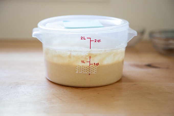 A 2-quart container holding sourdough starter with its height marked by a piece of washi tape.