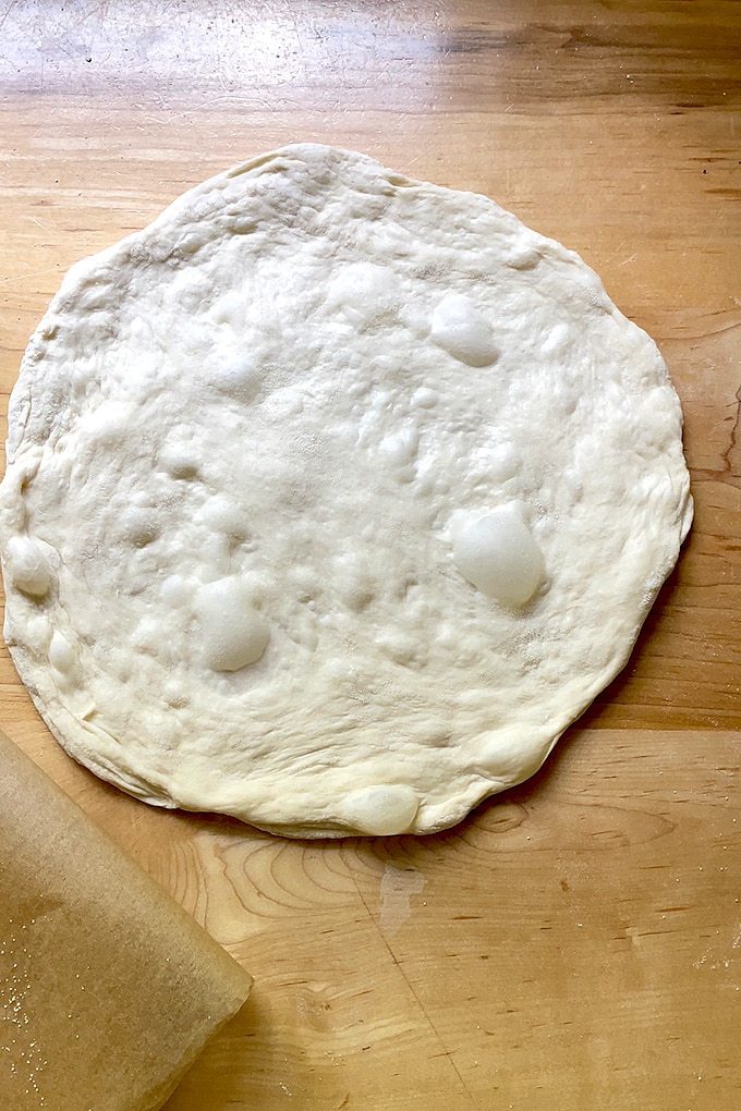 Unbaked pizza dough round on a counter top. 