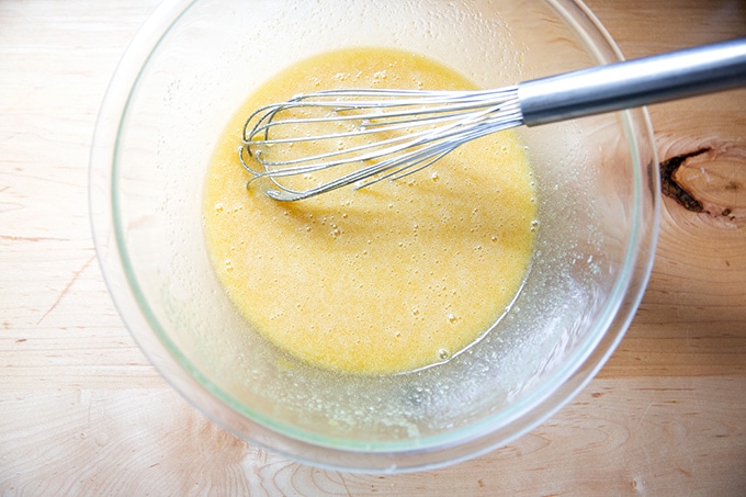 A large bowl filled with whisked sugar, butter, and eggs.