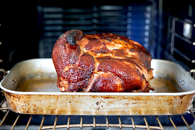 A brown sugar-glazed ham, just roasted in roasting pan in the oven.