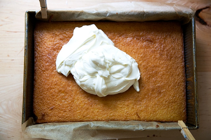A baked cake with topped with whipped cream-cream cheese frosting.