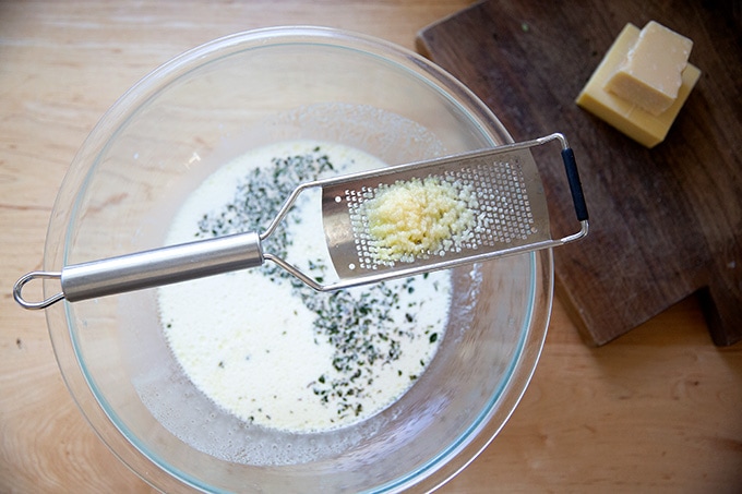 A microplane grater propped on a bowl topped with minced garlic.