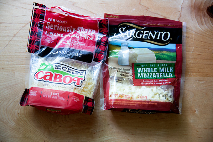 Two types of grated cheese: Cabot cheddar and Sargento mozzarella.
