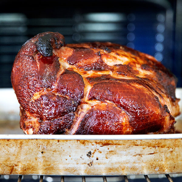 A brown sugar glazed ham emerging from the oven.