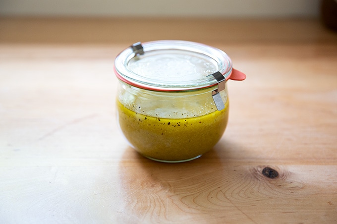 A jar of Greek salad dressing on a countertop.