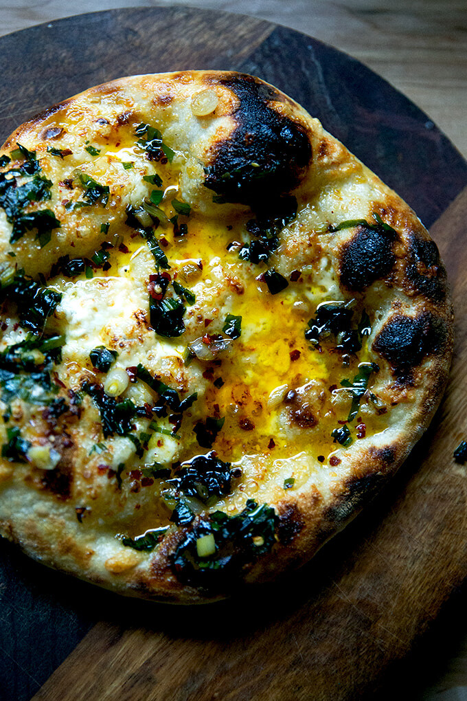 A just-baked sourdough pizza crust topped with sizzling ramp oil.
