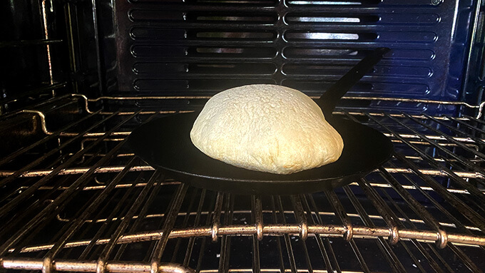A pita cooking on a preheated skillet in the oven. 