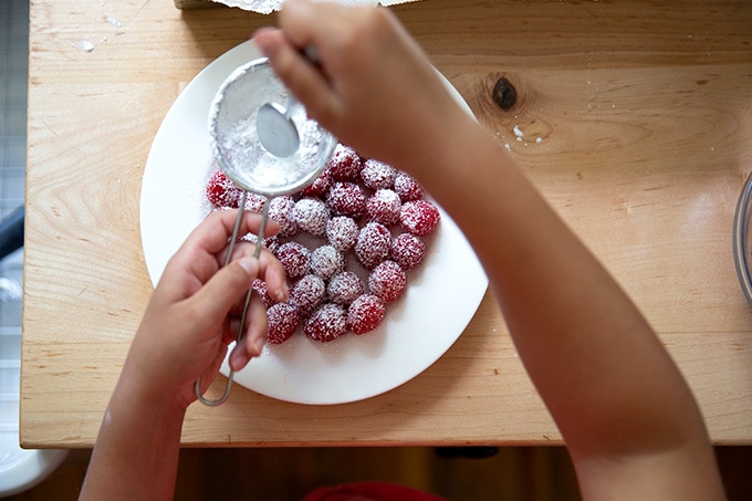 Sifting powdered sugar over a plate of raspberries.