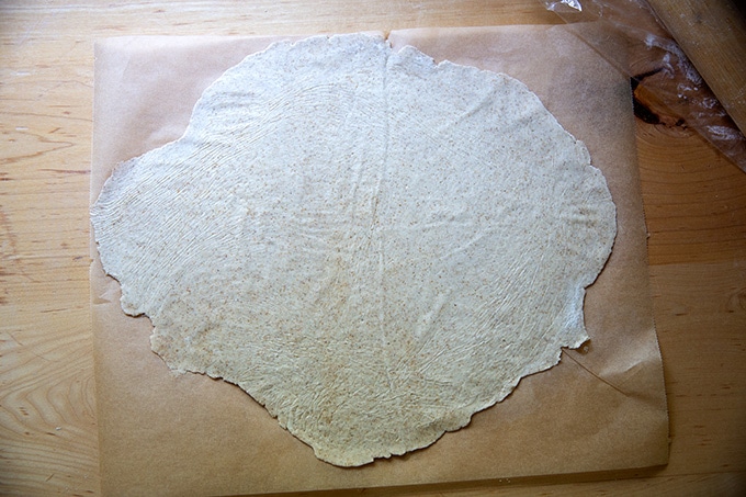 Rolled out sourdough cracker dough on a sheet of parchment paper.