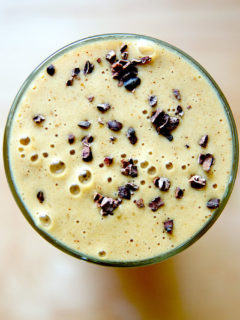 A glass filled with a coffee smoothie made with dates, banana, cauliflower, almond milk, almond butter, and cacao nibs.