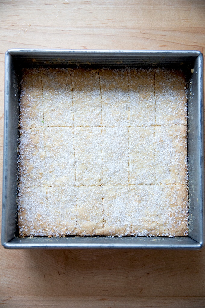 Just-baked shortbread, scored and sprinkled with sugar in a baking pan.