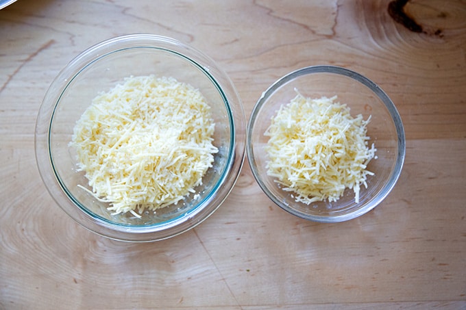 Two bowls of grated cheese on a countertop.