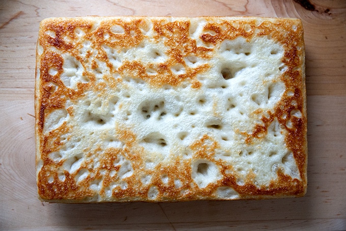 A parbaked Detroit-style pizza crust cooling upside down.