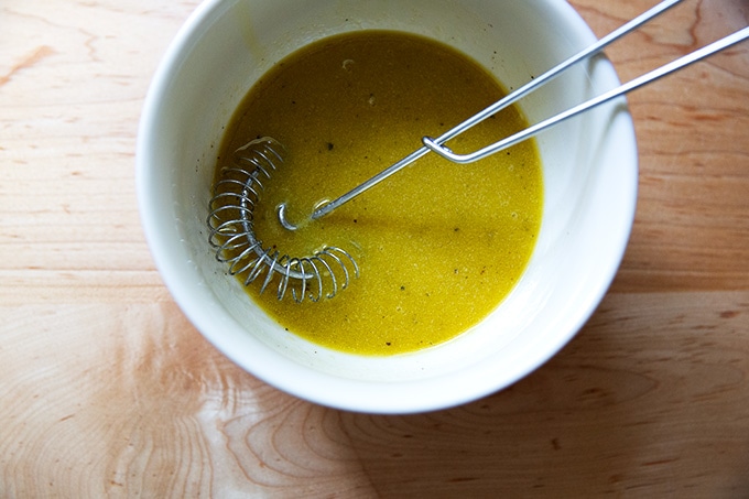A bowl of whisked Greek salad dressing with a whisk inside.
